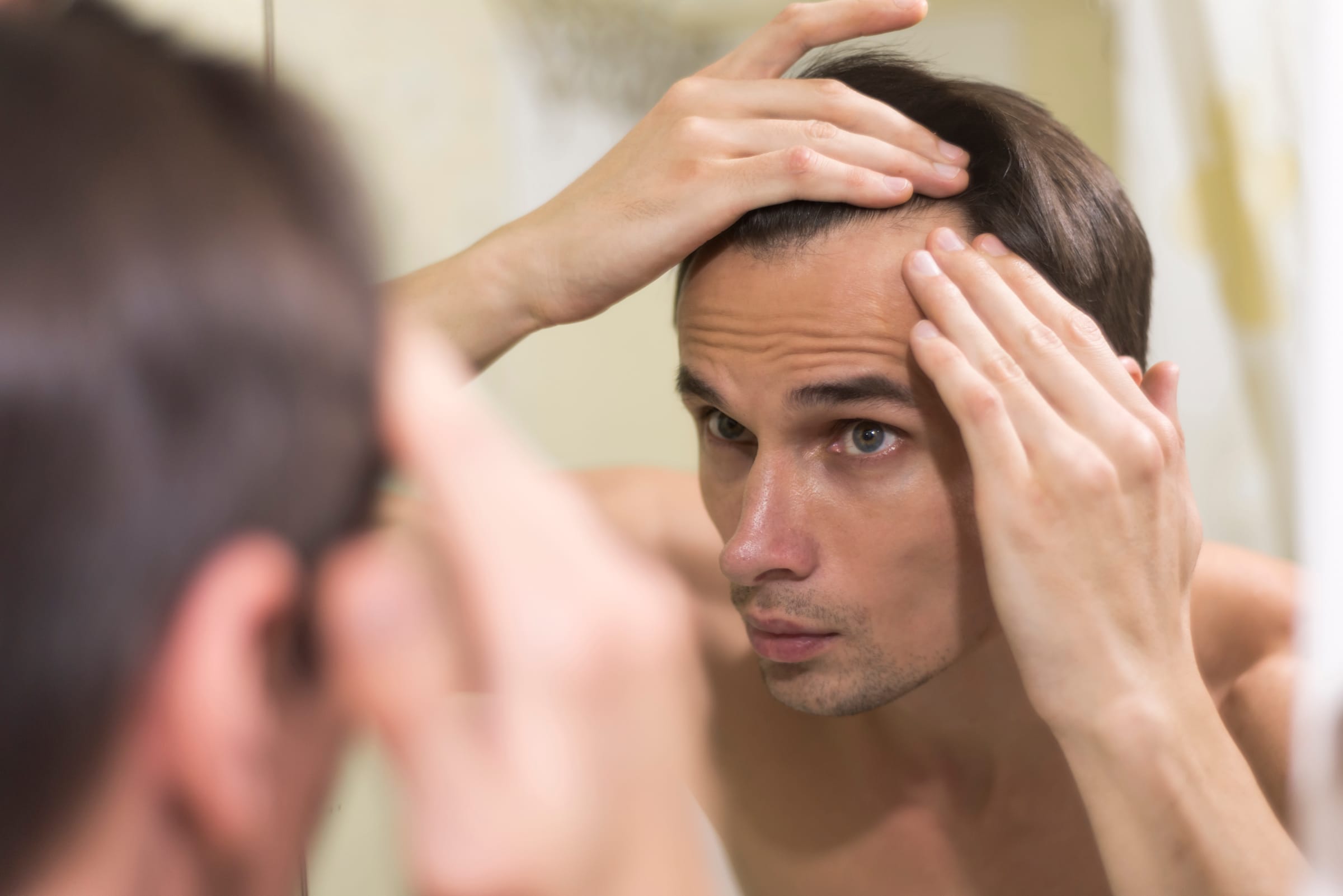 Man examining his hairline in a mirror